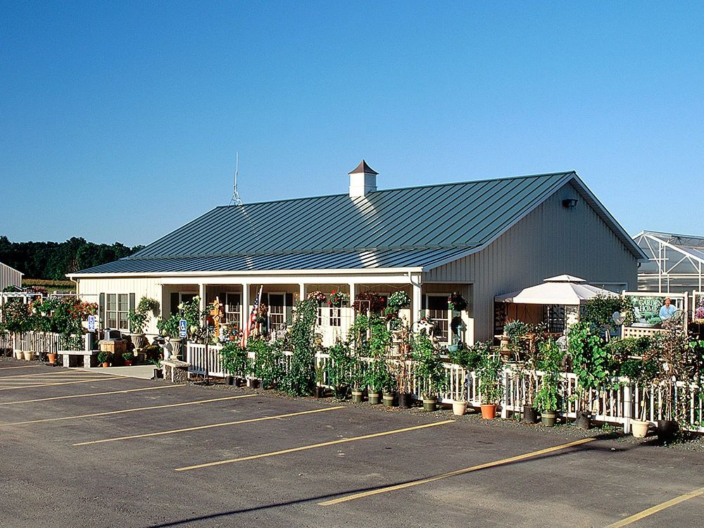 Long green metal roof above a plant display area