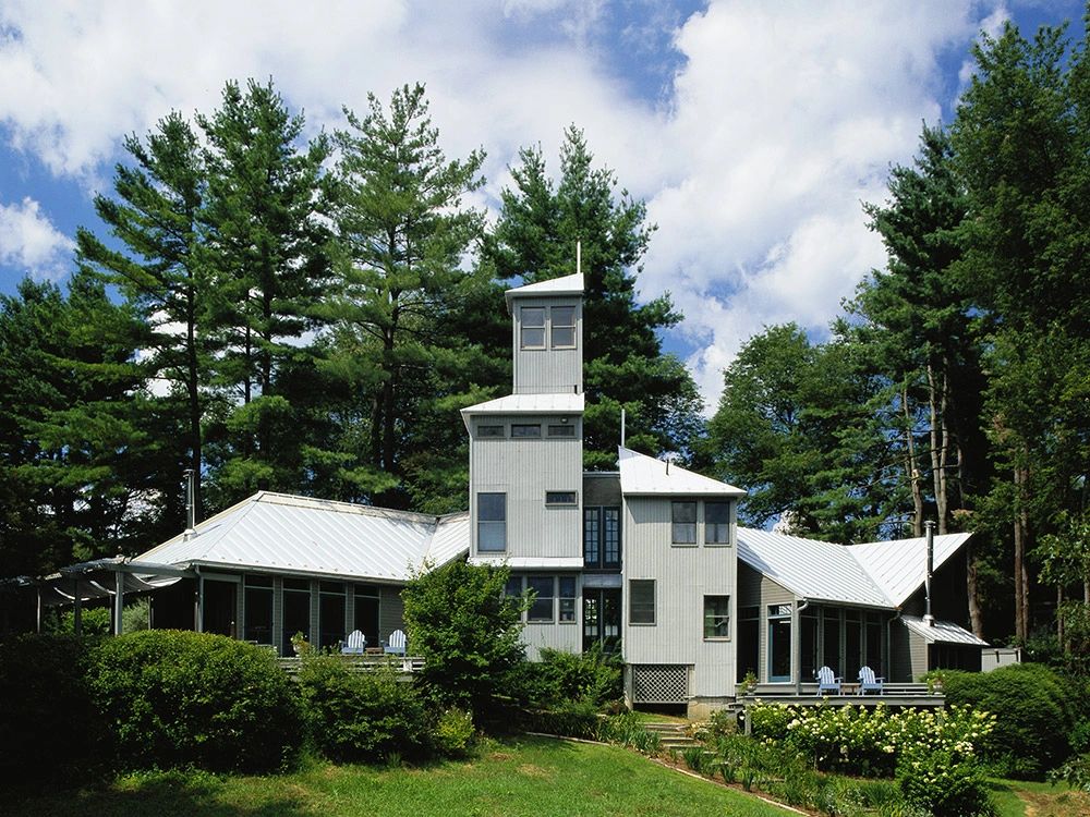 White building with multiple metal roof planes surrounded by trees