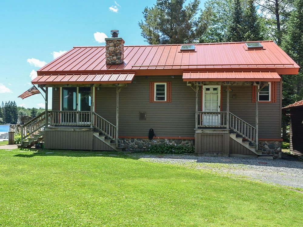 Home with a red standing seam roof beside a lawn