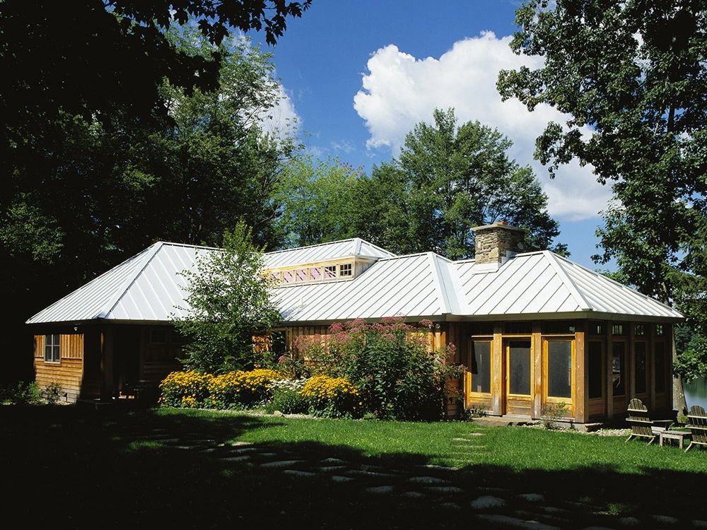 Low building with a light metal roof surrounded by trees