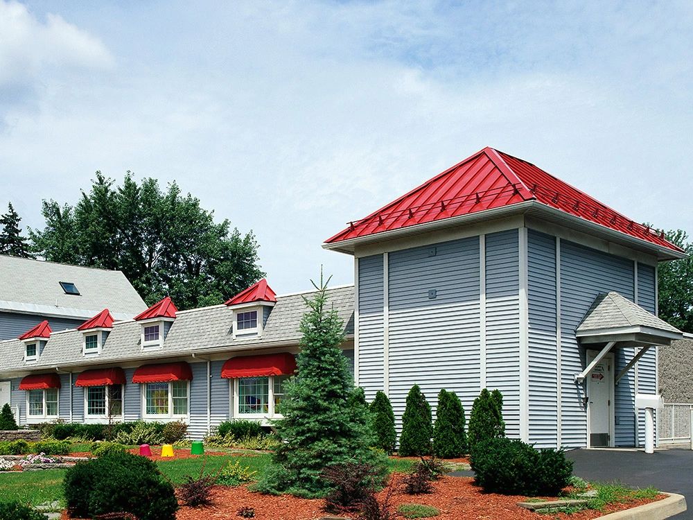 Red standing seam roof on a tower beside a landscaped building